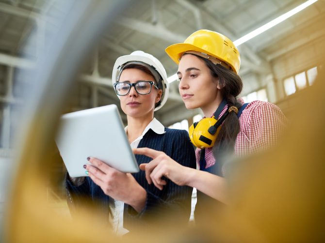 Two workers on the factory floor gaining insight from data on a tablet