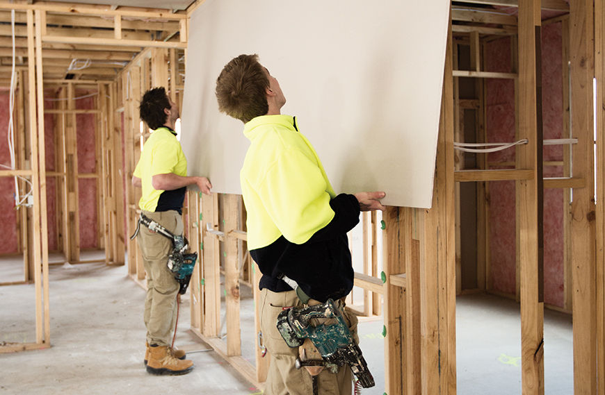 Two workers hanging sheetrock/drywall