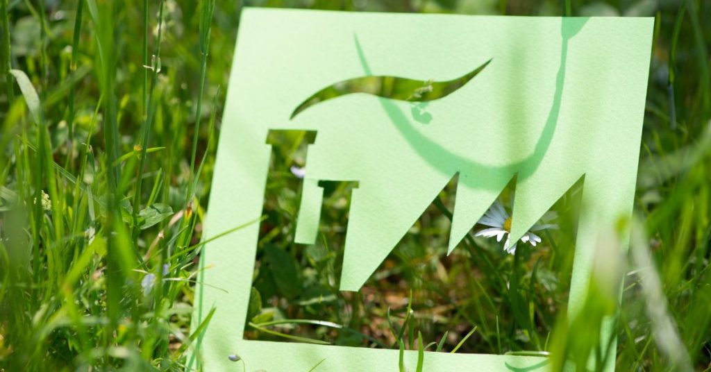 A stencil for a Factory Icon, held over grass